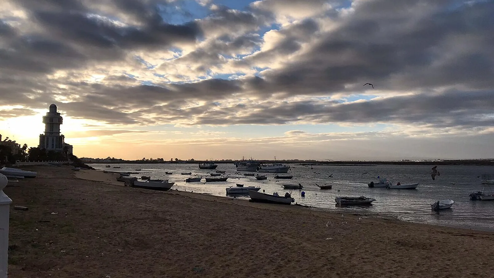 Faro de Isla Cristina y barcos en la costa de Huelva al atardecer